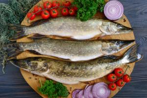 three fish on a cutting board with tomatoes and vegetables at Casa de la ghiol in Murighiol +17 photos
