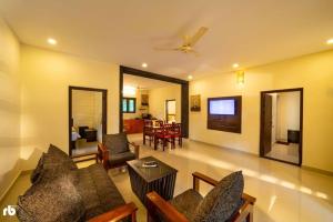 a living room with a couch and chairs and a tv at Kuruva Isles Jungle Resort in Wayanad