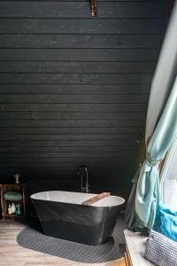 uma banheira na casa de banho com uma parede preta em SOPRANO - 'Virš Ąžuolų' - Forest SPA - Horses - Lake em Paplatelė