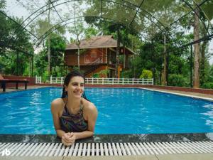 a woman is sitting next to a swimming pool at Kuruva Isles Jungle Resort in Wayanad +24 photos
