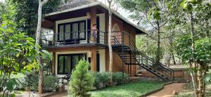 a woman standing on the balcony of a house at Kuruva Isles Jungle Resort in Wayanad
