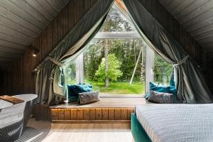 um quarto com uma cama e uma grande janela em SOPRANO - 'Virš Ąžuolų' - Forest SPA - Horses - Lake em Paplatelė