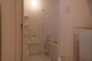 uma casa de banho branca com um chuveiro e um lavatório. em RIVER VILLAS HIROSHIMA em Hiroshima