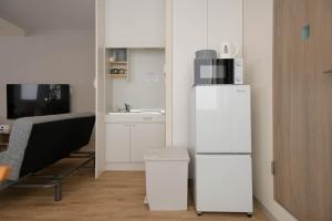 a white kitchen with a refrigerator and a table at RIVER VILLAS HIROSHIMA in Hiroshima