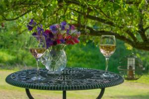 due bicchieri di vino e un vaso di fiori su un tavolo di Badgers Sett a Chipping Campden