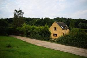 a house in a field next to a dirt road at Badgers Sett in Chipping Campden