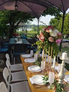 długi stół z białymi talerzami i kwiatami w obiekcie Vila Mila Riverside Apartments w mieście Smederevo
