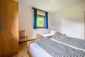 ein Schlafzimmer mit einem Bett, einem Fenster und einem Stuhl in der Unterkunft Ciasa La Palsa App 2 in St. Vigil