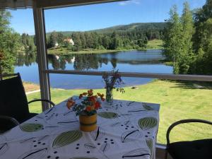 a table with a view of a lake from a window at Mysigt fritidshus och annex med eget sjöläge! in Torsby