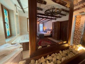 Kapadokya Konak في أوشيسار: حمام مع مرآة وحوض استحمام وغرفة نوم