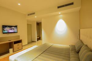 a bedroom with a bed and a tv on a wall at Heliconia Park Port Harcourt Hotel and Suites in Port Harcourt