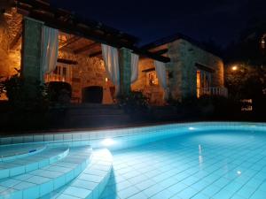 a swimming pool in front of a house at night at Rock House's Villa Melody in Platanias