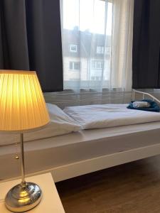 a bed with a lamp on a table next to a window at Apartment KENNEDY in Bremerhaven