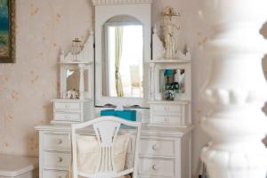 a white dressing table with a mirror and a white chair at Enchanted Manor in Niton