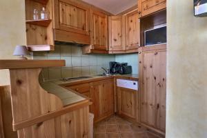 a small kitchen with wooden cabinets and a sink at Residence Plein Soleil in Méribel