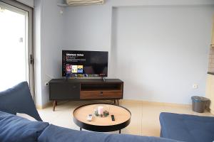 un salon avec un canapé bleu et une télévision dans l'établissement 2 Bedroom Apartment near the Athens Airport, Spata, à Spáta