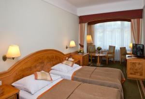 a hotel room with two beds and a table and chairs at Parkhotel Golf Marianske Lazne in Mariánské Lázně