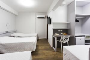 a bedroom with two beds and a desk with a chair at Tropikalya Prime Hotel in Balneário Camboriú