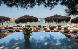 a table with chairs and straw umbrellas on a beach at Castello studios in Agia Anna Naxos