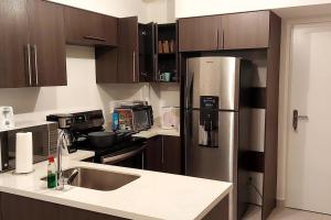 a kitchen with wooden cabinets and a stainless steel refrigerator at Altamira Cozy apartment with amazing views in Santo Domingo