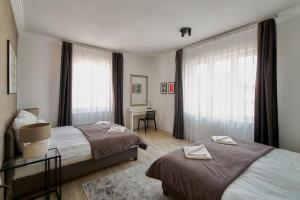 a bedroom with two beds and a desk and windows at Amazing Design Apartment Dohány str in Budapest