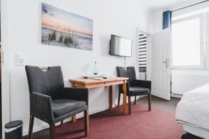 um quarto com uma secretária, 2 cadeiras e uma televisão em Hotel Aurora em Kappeln