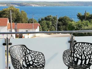 two chairs sitting on a balcony looking out at the ocean at Apartmani Deluxe in Jasenice