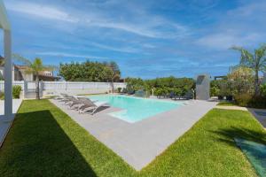 a swimming pool with lounge chairs in a yard at Villa White Luxury Residence in Marsala