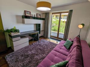 a living room with a purple couch and a desk at Juniper Apartment in Braşov
