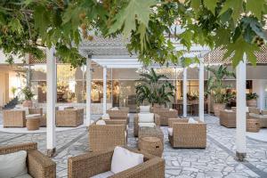 Leptos Panorama Hotel في كالاماكي: لوبى مع كراسي الخوص والطاولات والأشجار