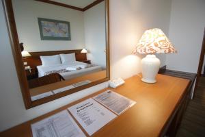 a hotel room with a bed, desk and lamp at Park Avenue Hotel Sungai Petani in Sungai Petani