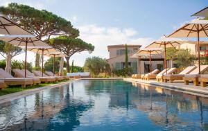 a swimming pool with lounge chairs and umbrellas at Hôtel L'Escalet in Ramatuelle
