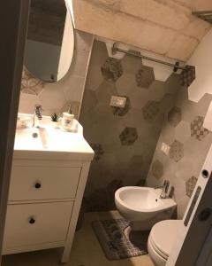 Un baño con lavabo, inodoro y espejo. en Dimora Nonna Martina, en Martina Franca
