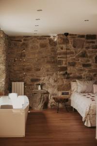 1 dormitorio con pared de piedra, cama y mesa en La Caseta de Subirana en Les Llosses
