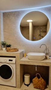 a bathroom with a sink and a washing machine at Salt & Stone Villa in Pag
