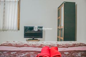 un par de zapatillas rojas en una cama con TV en Villa Mawar Adinda Kuningan Syariah RedPartner, 