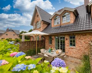 a brick house with a patio and flowers at Haus Sylter Inselglück in Tinnum