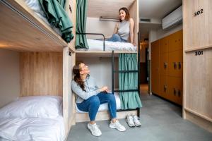 阿姆斯特丹The Bee Hostel的宿舍间的双层床上,有两名女性
