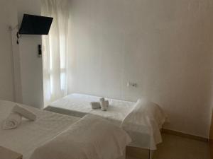 a white bedroom with two beds with towels on them at APARTAMENTO PINAPLAYA in Grao de Castellón