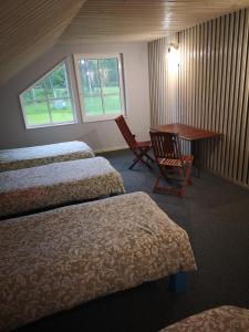 a room with three beds and a table and a desk at Palūšės Kempingas (kambariai) in Palūšė