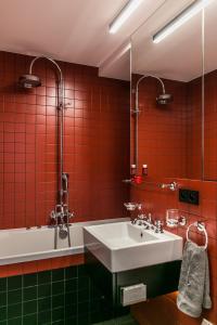 a red tiled bathroom with a sink and a tub at Apartament Złota in Warsaw