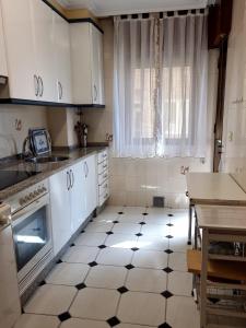 eine Küche mit weißen Schränken und einem schwarz-weißen Fliesenboden in der Unterkunft Soleado piso 4 habit a pie de playa Sanxenxo in Sanxenxo