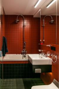 a bathroom with a sink and a tub and red tiles at Apartament Złota in Warsaw