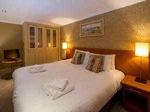 a bedroom with a large white bed with towels on it at The Bulkeley Hotel in Beaumaris