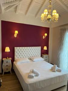 a bedroom with a large white bed with a red wall at Theokleia_guest house in Kavála