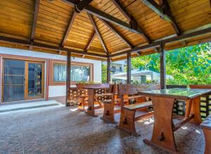 un patio con mesas y bancos de madera y techo de madera. en Vila Cataleya en Venus
