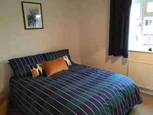 a bedroom with a blue bed with pillows and a window at KB21 Attractive 2 Bed House, pets/long stays with easy links to London, Brighton and Gatwick in Roffey