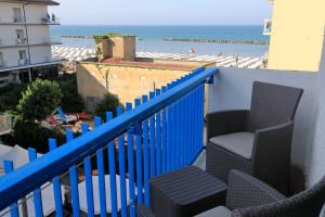 a balcony with chairs and a blue fence and the ocean at Hotel Lauretta in Bellaria-Igea Marina