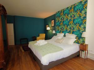 a bedroom with a large bed with a blue wall at Maison d'hôtes de charme - Au Lys Blanc in Châteauroux