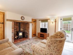 a living room with two chairs and a fireplace at Postbox Cottage in Thetford